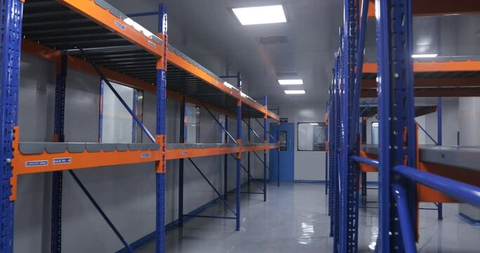 Empty warehouse area cleanroom with colored racks for storage and epoxy flooring in a pharmaceutical manufacturing factory for active pharma ingredients, specialty chemicals, hazardous chemical	