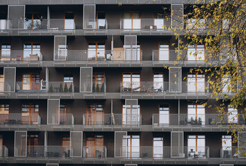 Modern European house with rows of balconies with decorative latticework and railings on summer sunny day