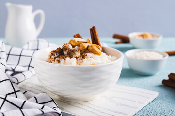 Rice pudding with cinnamon and cashews in a bowl on the table
