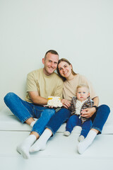 A young family with a baby in their arms sits with a cake in their hands. A married couple is...