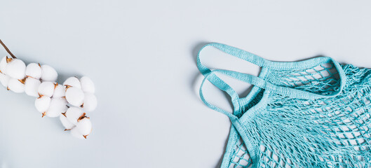 Concept of refusing plastic bags. String bag and cotton branch on a blue background web banner