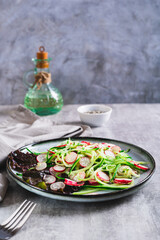 Fresh vitamin salad of cucumber and radish on a plate on the table vertical view