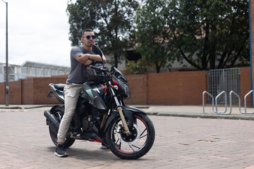 young motorcyclist man with glasses with his motorcycle on the street about to start a biker trip