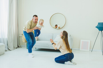 Young parents are playing with their little 10-month-old son. Mom and dad are playing with their...