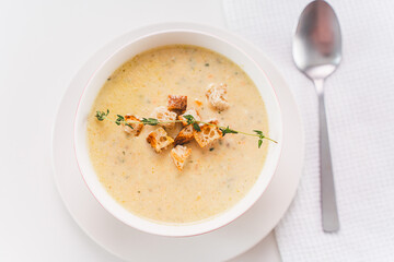 Cream soup with croutons and thyme in a white plate on the table. Selected focus