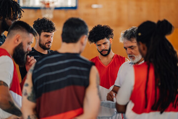 Diverse basketball player standing back while coach speaking about tactic