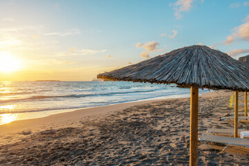 View of tropical beach with umbrelles during sunset.