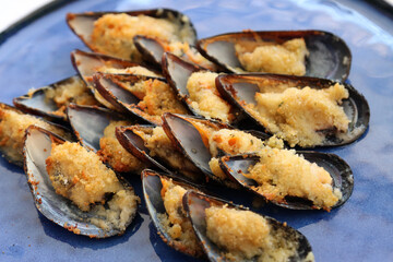Plate of mussels au gratin. Mussels covered in wine and stuffed with breadcrumbs and Parmesan, finally grating them in the oven