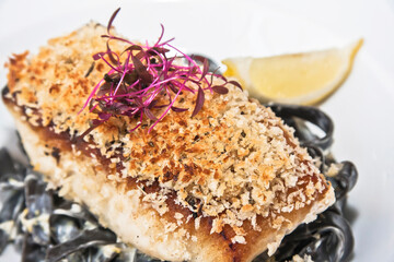 Fish fillet, breaded sea bass fillet with black fettuccine and beet sprouts, gourmet food