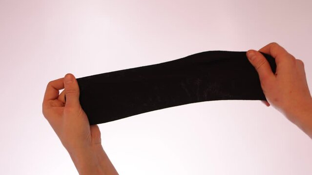 Demonstration of the structure of black socks by the hands of a man