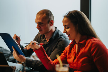 Young business entrepreneurs in a meeting, actively discussing strategy and collaborating with laptops and documents. Focused teamwork and modern work environment.