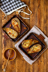 two servings of delicious baked pears with honey on a wooden background