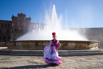 A pretty little girl dancing flamenco dressed in a white dress with pink frills and fringes in a...
