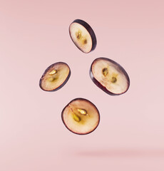 Fresh organic Blue Grape falling in the air isolated on pink background. Food levitation or zero...