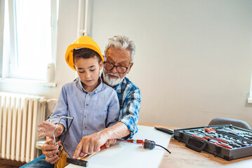 Important skills. Nice pleasant smart grandfather and grandson sitting together and the table and...