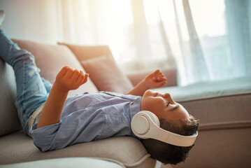Little boy in headphones listening to music. Stylish teen boy listening music in headphones. School...