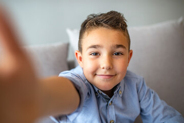 Cute little boy taking selfie on light background. Happy little boy with healthy teeth taking...