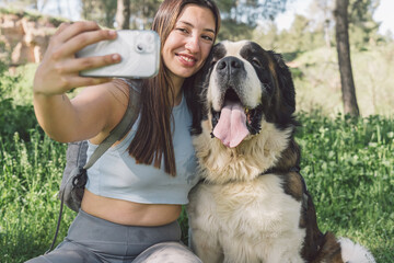 Woman taking selfie with happy dog in park. Cheerful woman captures a selfie with her joyful...