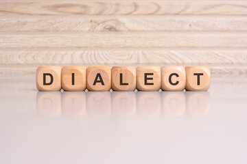 wooden blocks displaying the word 'DIALECT' arranged on a glossy gray surface