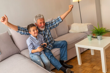 Grandfather and grandson playing computer games. Boy and his grandfather with video game...
