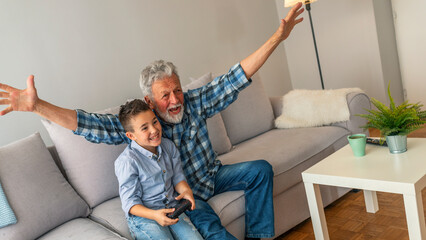 Grandfather and grandson playing computer games. Boy and his grandfather with video game...