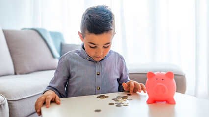 Portrait of a little boy putting money on a moneybox. Portrait of cute little boy with piggy bank...