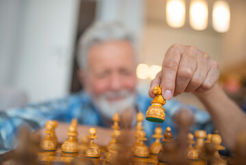 Elderly man making a move with chess piece. Old man making chess move. Senior man play with chess...