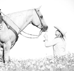 Cowgirl with palomino horse in field of flowers
