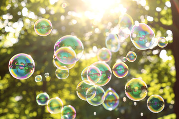 rainbow soap bubbles fly against background of summer green leaves