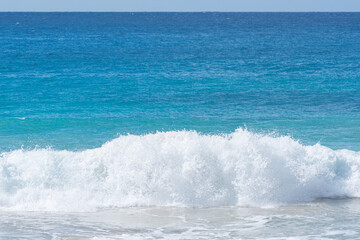 Aqua blue ocean water with wave breaking on shore