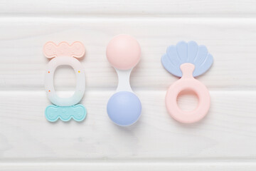 Colorful baby rattles and toys on wooden background, top view