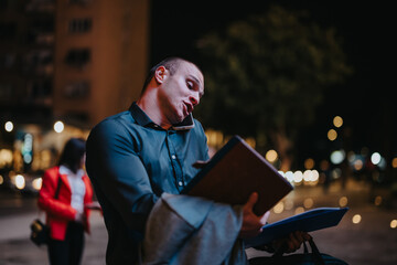 A young corporate businessman gathering information while multitasking on the phone and holding...