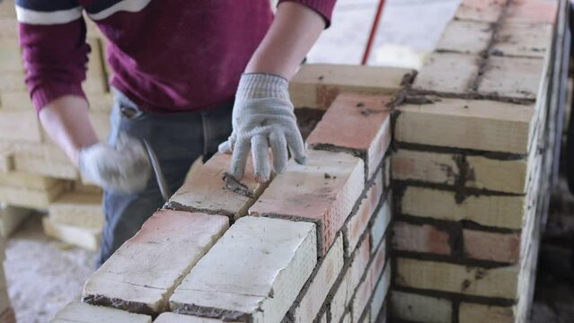 Construction worker is expertly laying bricks at the construction site with precision and skill