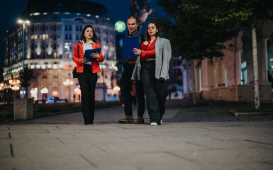 Young professionals having an outdoor business meeting, discussing project details in an urban...