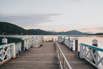 Obraz premium Wooden dock with a chair beside the water's edge