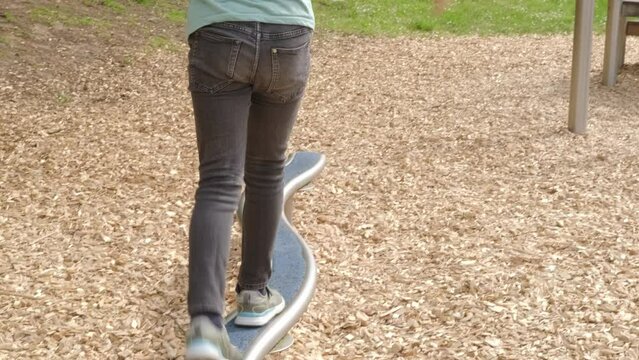 Young child walking, balancing on sports log at playground, developing coordination and motor skills, maintain balance on sports equipment, Coordination Development