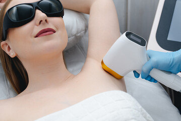 laser epilation, hair removal procedure, young beautiful caucasian smiling woman lying on couch in...