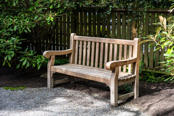 Classic wood seat bench with backrest outside in a woodland garden, peaceful place for rest and...