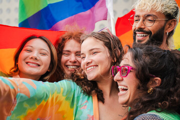 Close up portrait of a group of LGBT poeple having fun celebrating the gay pride day with a rainbow...