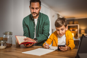 Father with book help son who copy notes from mobile phone at home