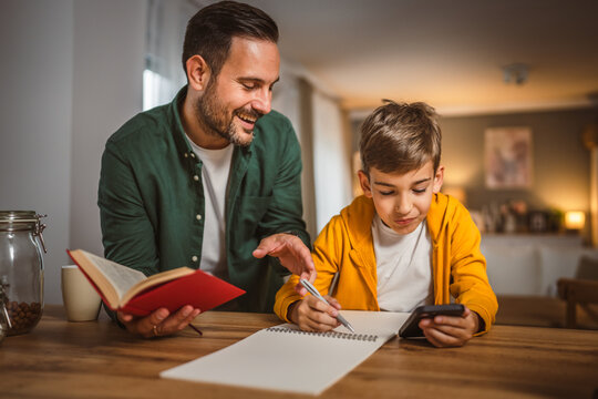 Father with book help son who copy notes from mobile phone at home
