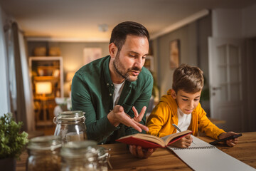 Father with book help son who copy notes from mobile phone at home