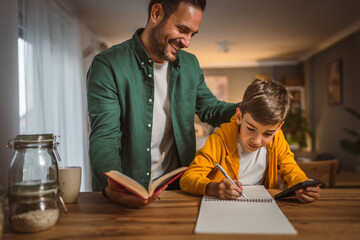 Father with book help son who copy notes from mobile phone at home