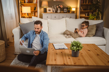 Father work from home use laptop with son at background
