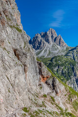 Dolomiti Alps beautiful mountain landscape. Rocky tower alpine summits in the Dolomites. Summer mountain scenic view on the hiking trekking path in the green mountain valley and blue sky with clouds