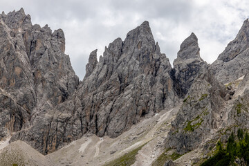 Dolomiti Alps beautiful mountain landscape. Rocky tower alpine summits in the Dolomites. Summer mountain scenic view on the hiking trekking path in the green mountain valley and blue sky with clouds