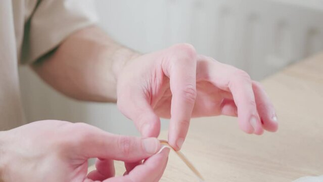 Male fingers closeup, man performing self-administered medical test pricking finger and collecting blood in tube, rapid diagnostic at-home test, blood sample collection, DIY medical test