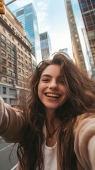 Fototapeta premium Young woman takes a selfie in front of tall buildings in the city.