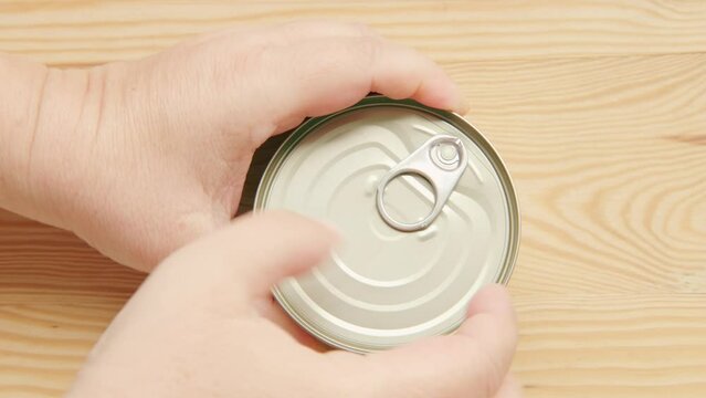 caucasian hands opens tin can on wooden board surface, opening with ring-pull opener, Independent living skills, Everyday kitchen essentials, everyday task preparing food at home