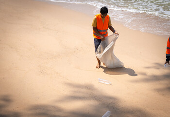 A man is picking up trash on the beach